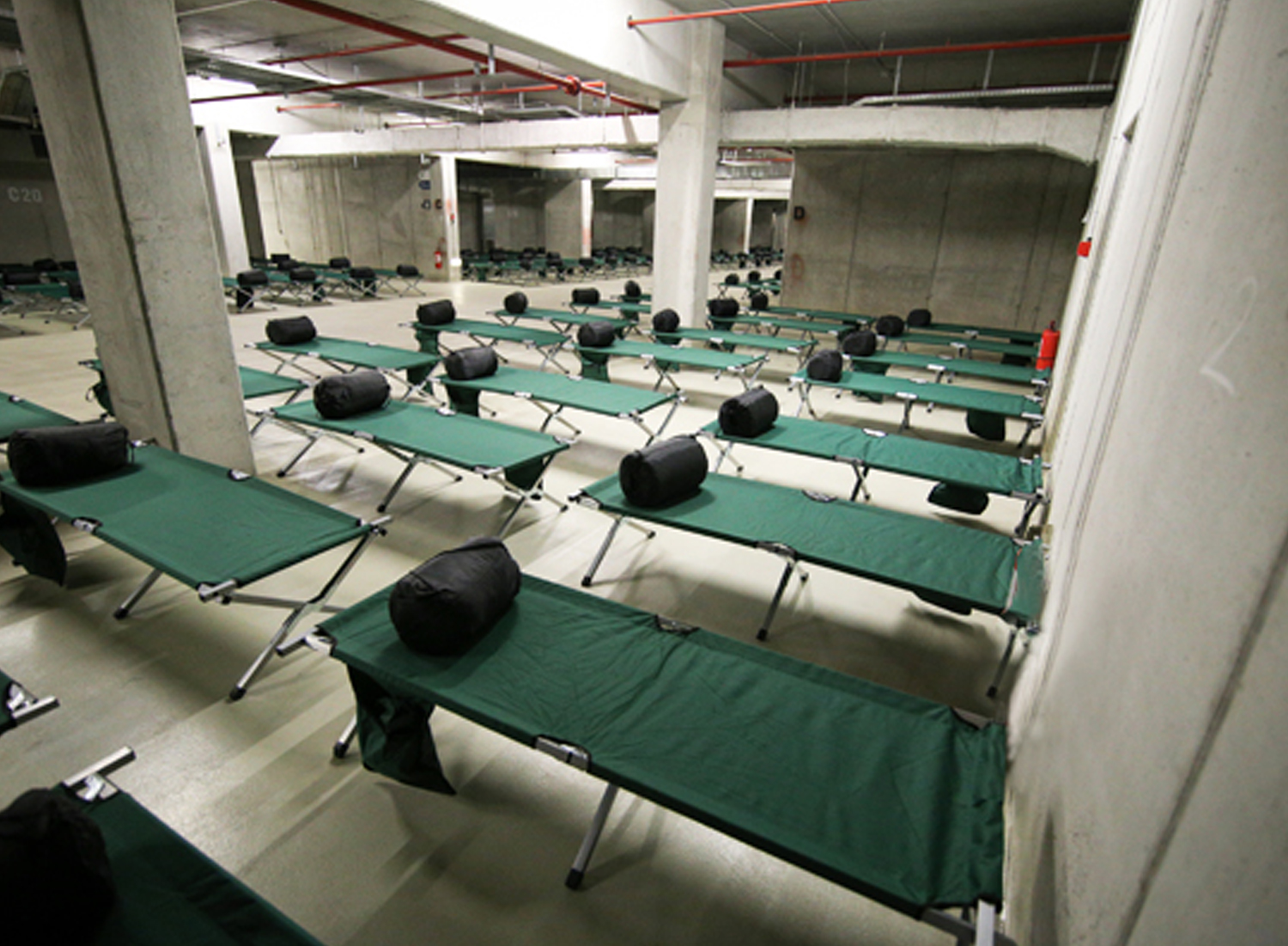 Grande salle avec cloison de béton où est disposer des lits de camps